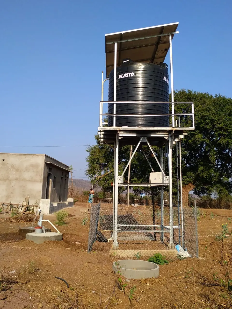 Solar-powered drinking-water point: tank on a steel stand under a solar panel