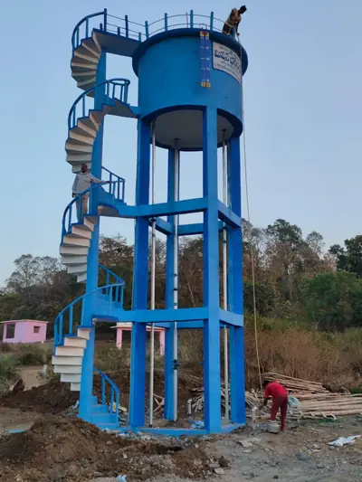 Blue RCC overhead tank with a spiral staircase, workers finishing it