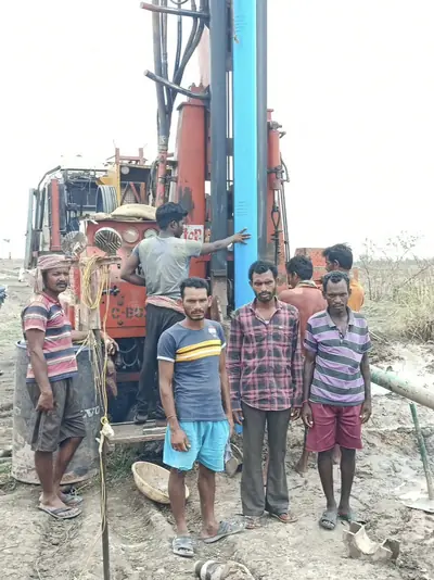 Drilling crew beside the rig as a blue casing pipe is lowered