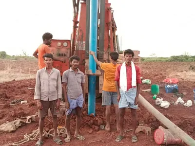 Crew at the rig as a blue casing pipe goes into a new borewell